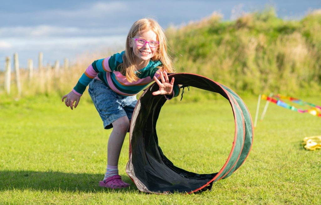 a young girl posting her arm through a tunnel